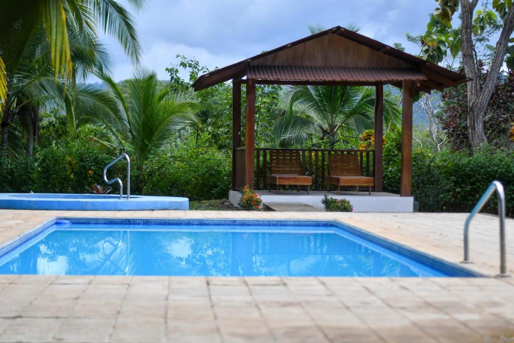 a swimming pool with a gazebo next to a house at Tarcoles Birding Lodge in Tárcoles