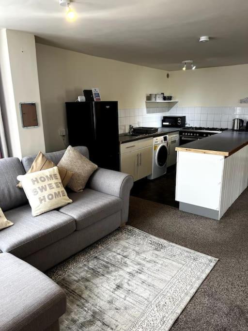 a living room with a couch and a kitchen at The Hideaway Holywell 1 in Holywell