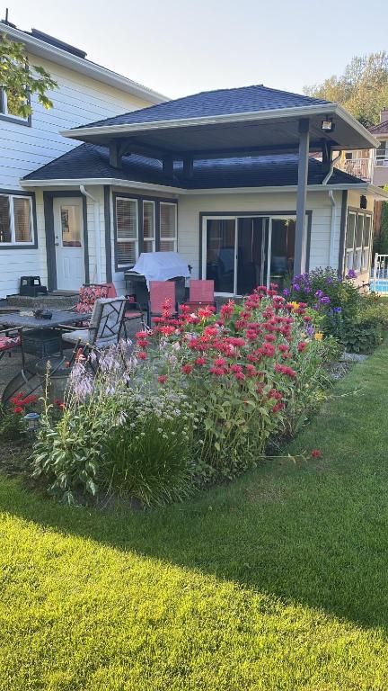 una casa con un jardín con flores en el patio en WHITEWATER COTTAGE, en Chilliwack