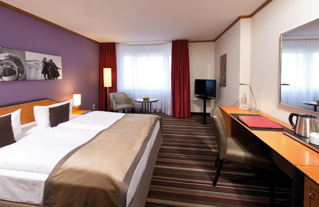 um quarto de hotel com uma cama grande e uma secretária em Leonardo Hotel Weimar em Weimar