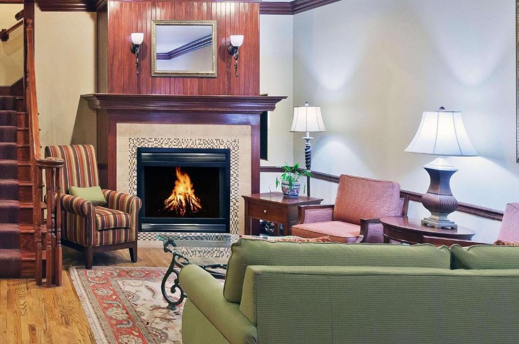 a living room with a fireplace and a couch and chairs at Country Inn & Suites by Radisson, Tulsa, OK in Tulsa