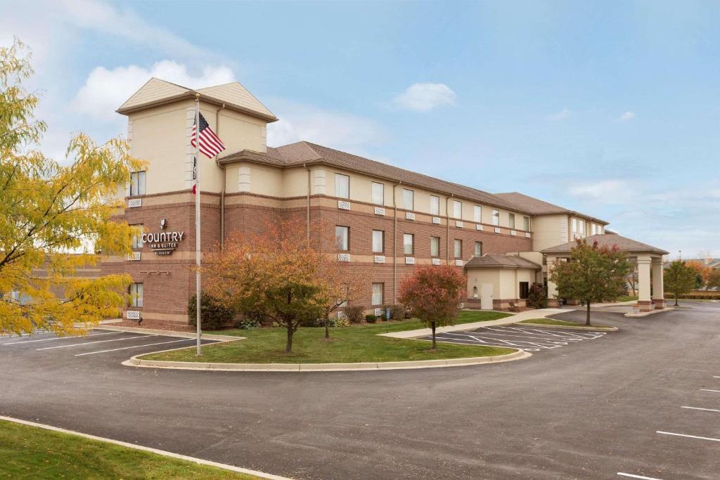 un edificio con una bandera americana en un estacionamiento en Country Inn & Suites by Radisson, Dayton South, OH, en Dayton