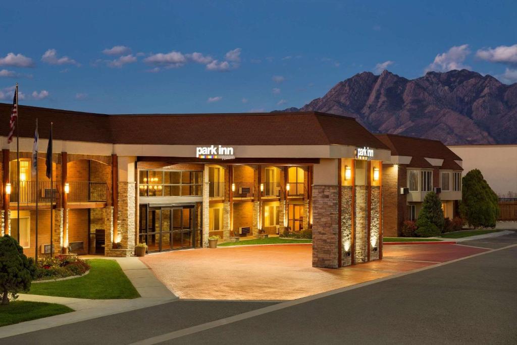 a large building with mountains in the background at Park Inn by Radisson Salt Lake City -Midvale in Midvale
