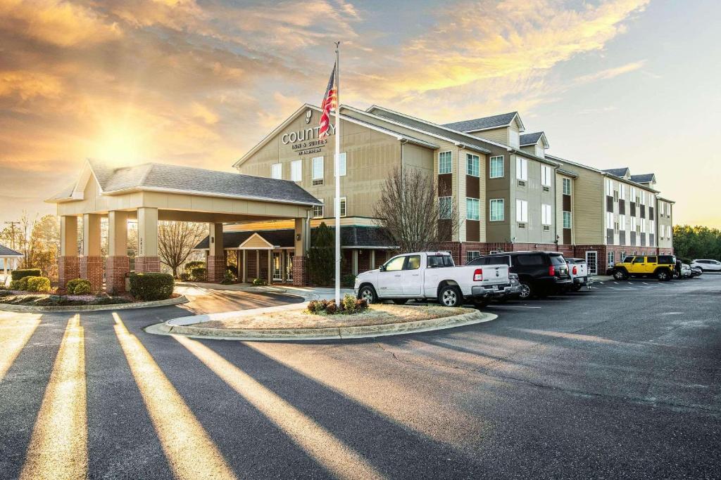 ein Hotel mit einer Flagge auf einem Parkplatz in der Unterkunft Country Inn & Suites by Radisson, El Dorado, AR in El Dorado