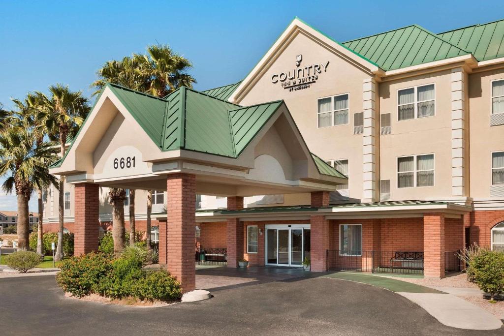 Country Inn & Suites by Radisson, Tucson Airport, AZ في توسان: مبنى الفندق بالسطح الأخضر والنخيل