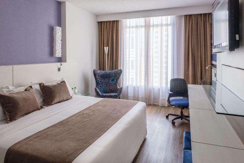 Habitación de hotel con cama y silla en Radisson Hotel Curitiba en Curitiba