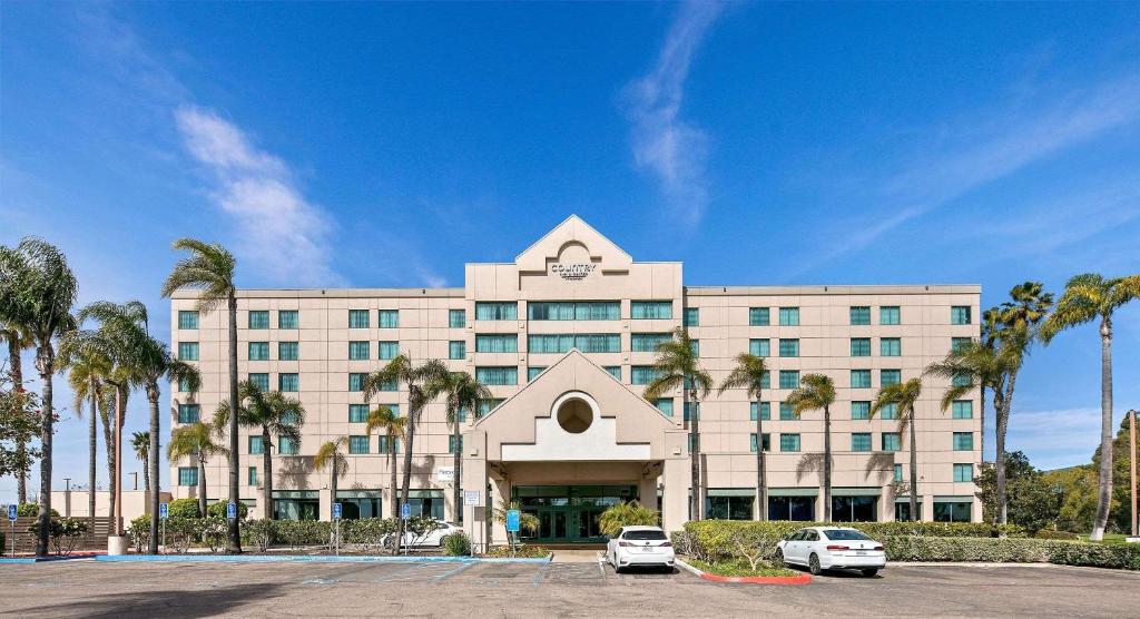 un gran edificio blanco con palmeras delante en Country Inn & Suites by Radisson, San Diego North, CA, en Mira Mesa