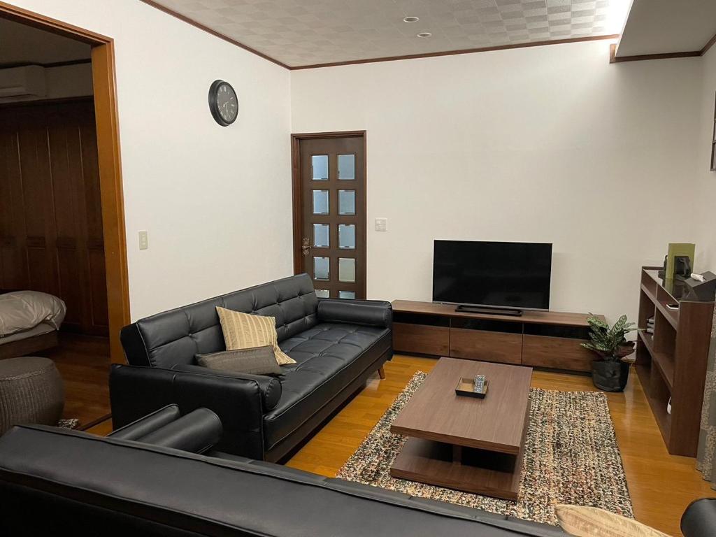 sala de estar con sofá negro y TV de pantalla plana en Villa Souan - Vacation STAY 15588 en Mobara