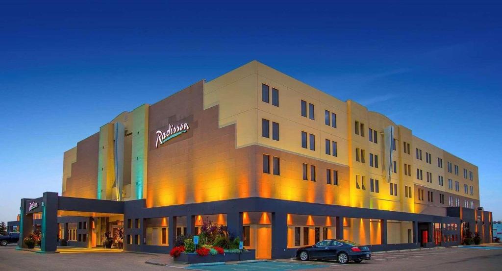 a building with a car parked in front of it at Radisson Hotel Red Deer in Red Deer