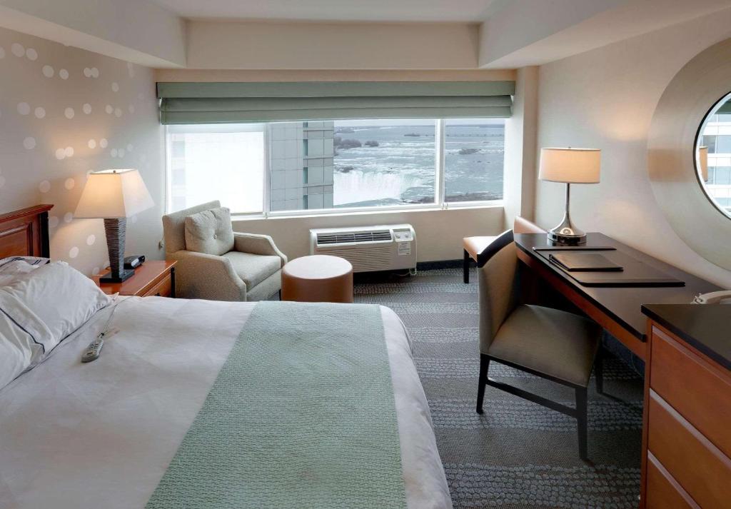 a hotel room with a bed and a desk and a window at Radisson Hotel & Suites Fallsview in Niagara Falls