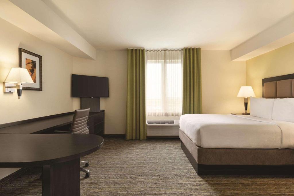 a hotel room with a bed and a desk and a table at Park Inn by Radisson, Calgary Airport North, AB in Calgary