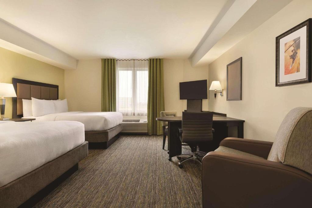 a hotel room with two beds and a desk at Park Inn by Radisson, Calgary Airport North, AB in Calgary