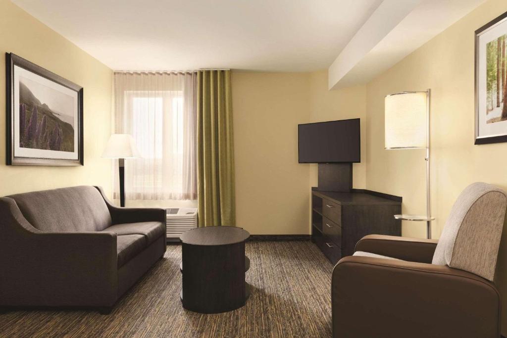 a hotel room with a couch and chairs and a tv at Park Inn by Radisson, Calgary Airport North, AB in Calgary