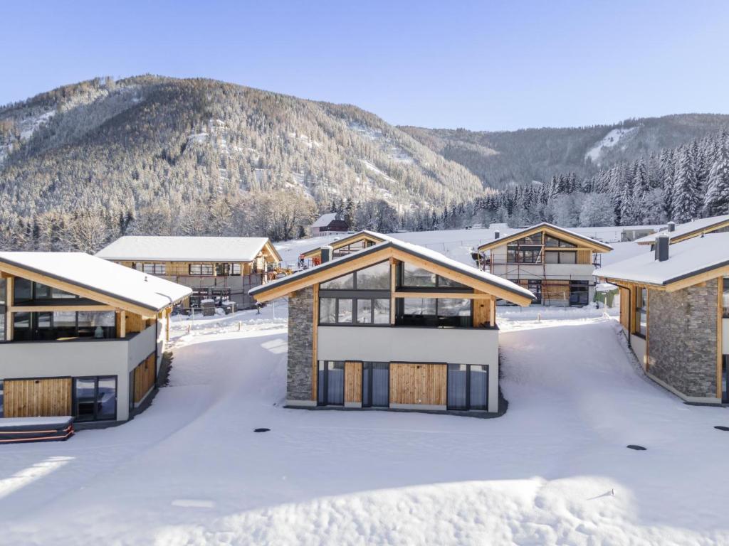 a group of buildings in the snow with mountains in the background at Grebenzen Top Chalet Mazzel in Sankt Lambrecht