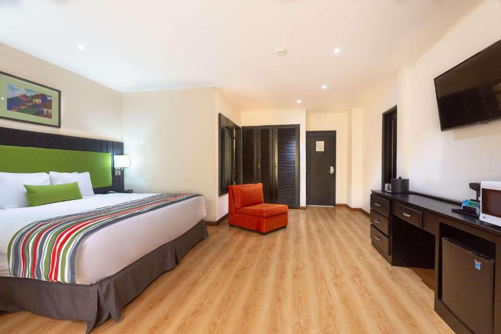 a hotel room with a large bed and a red chair at Country Inn & Suites by Radisson, San Jose Aeropuerto, Costa Rica in San José