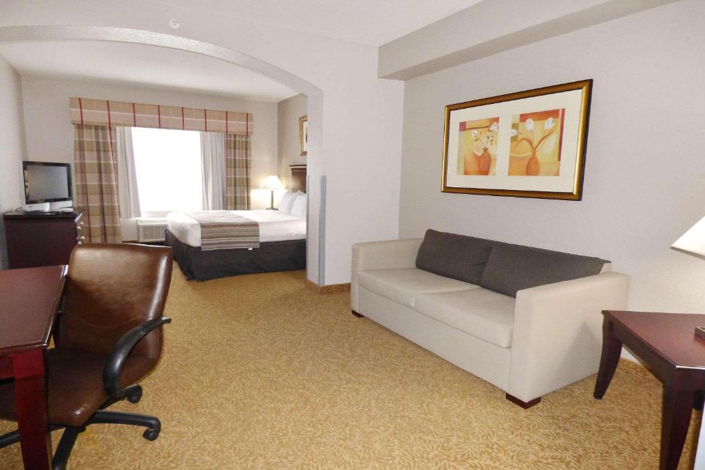 a hotel room with a couch and a bed at Country Inn & Suites by Radisson, Pensacola West, FL in Pensacola