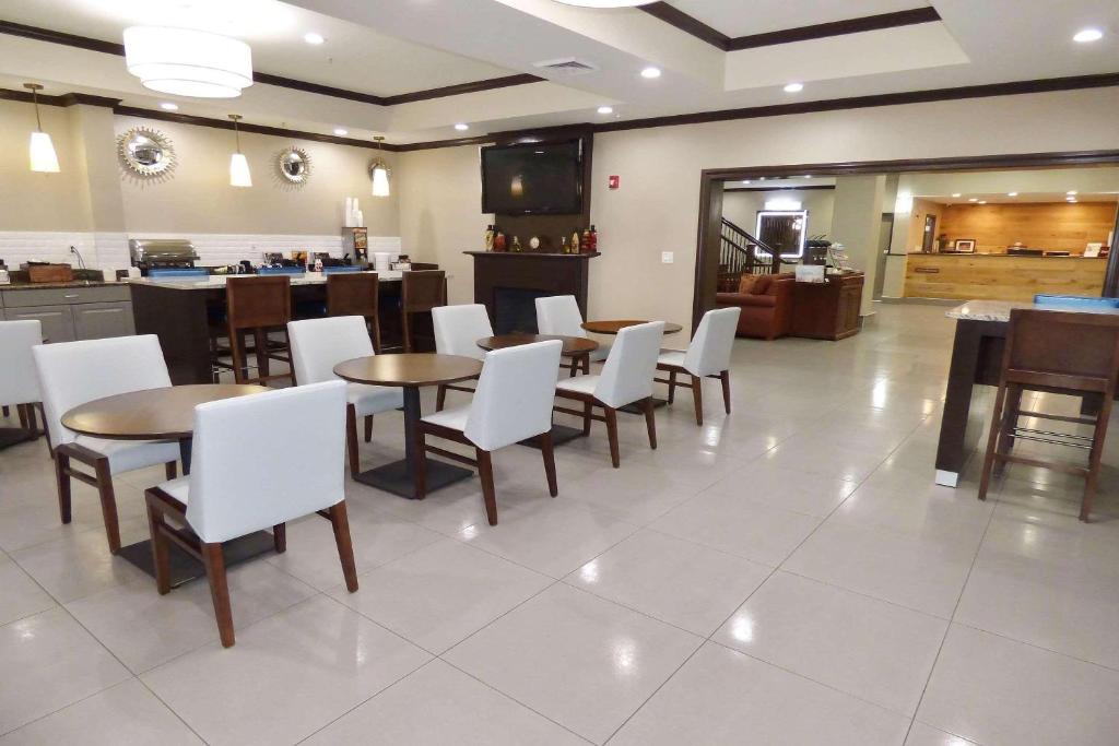 a restaurant with tables and white chairs and a kitchen at Country Inn & Suites by Radisson, Pensacola West, FL in Pensacola