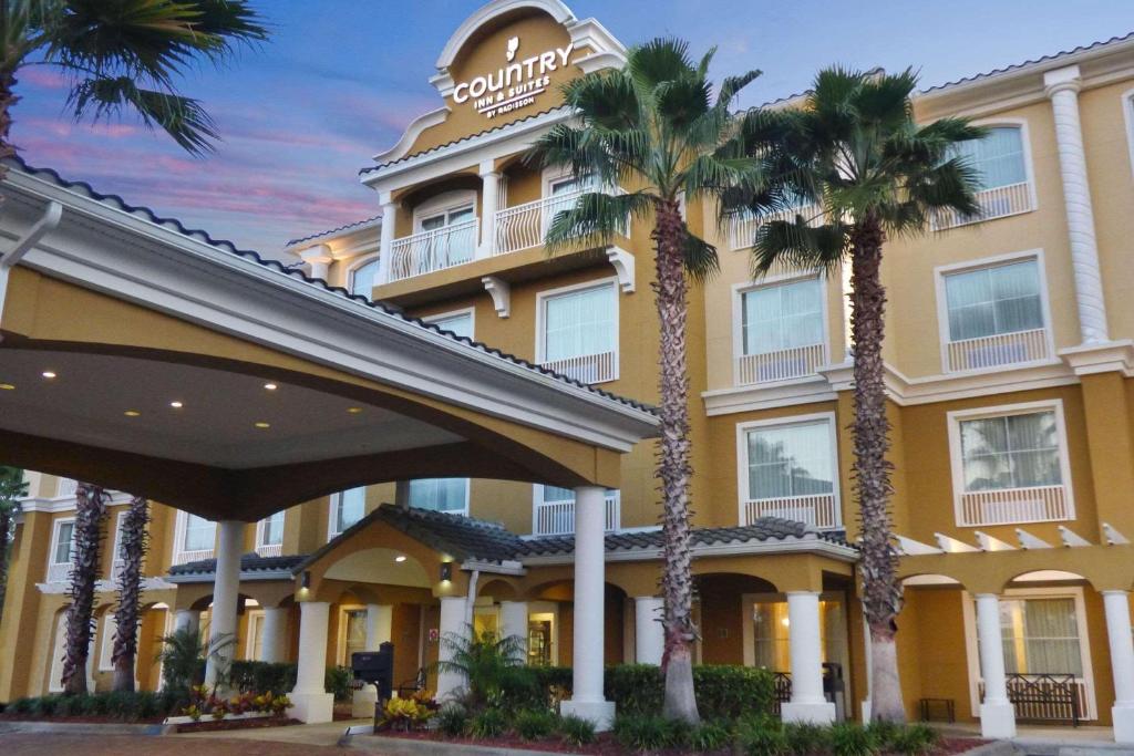 a hotel with palm trees in front of it at Country Inn & Suites by Radisson, Port Orange-Daytona, FL in Port Orange