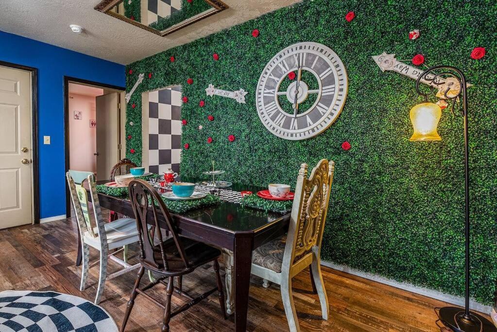 a dining room with a table and a clock on the wall at Alice- The Wonderland Experience in Salem