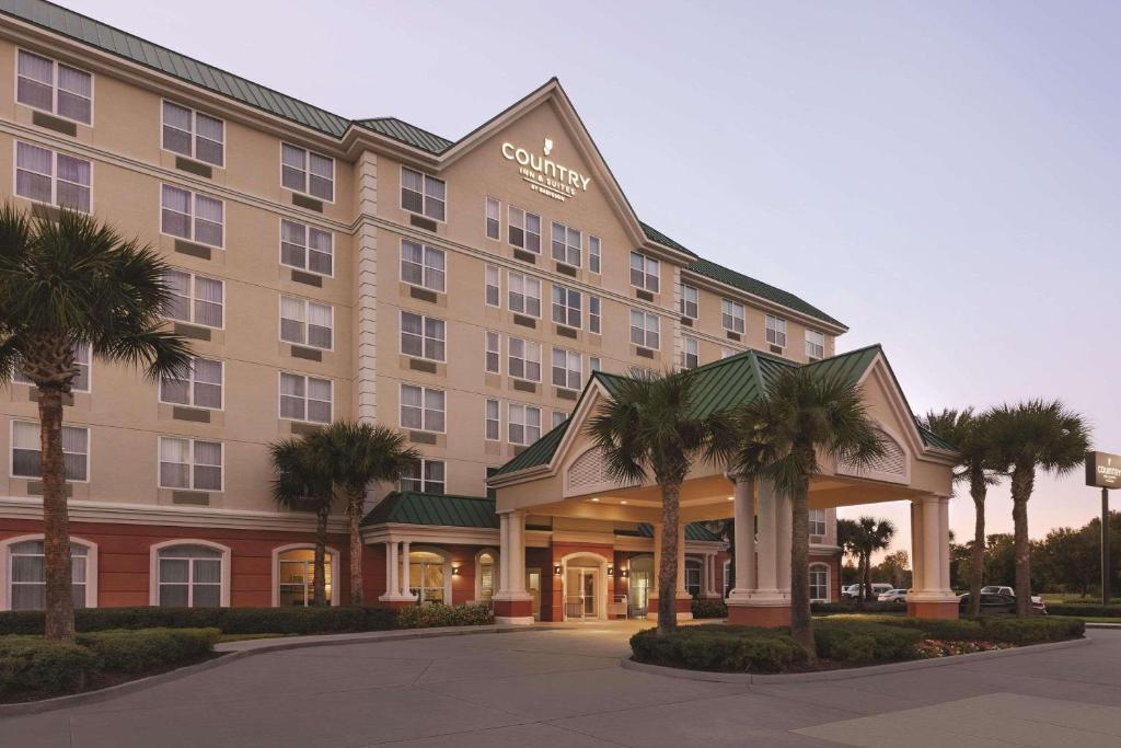 een hotelgebouw met palmbomen ervoor bij Country Inn & Suites by Radisson, Orlando Airport, FL in Orlando