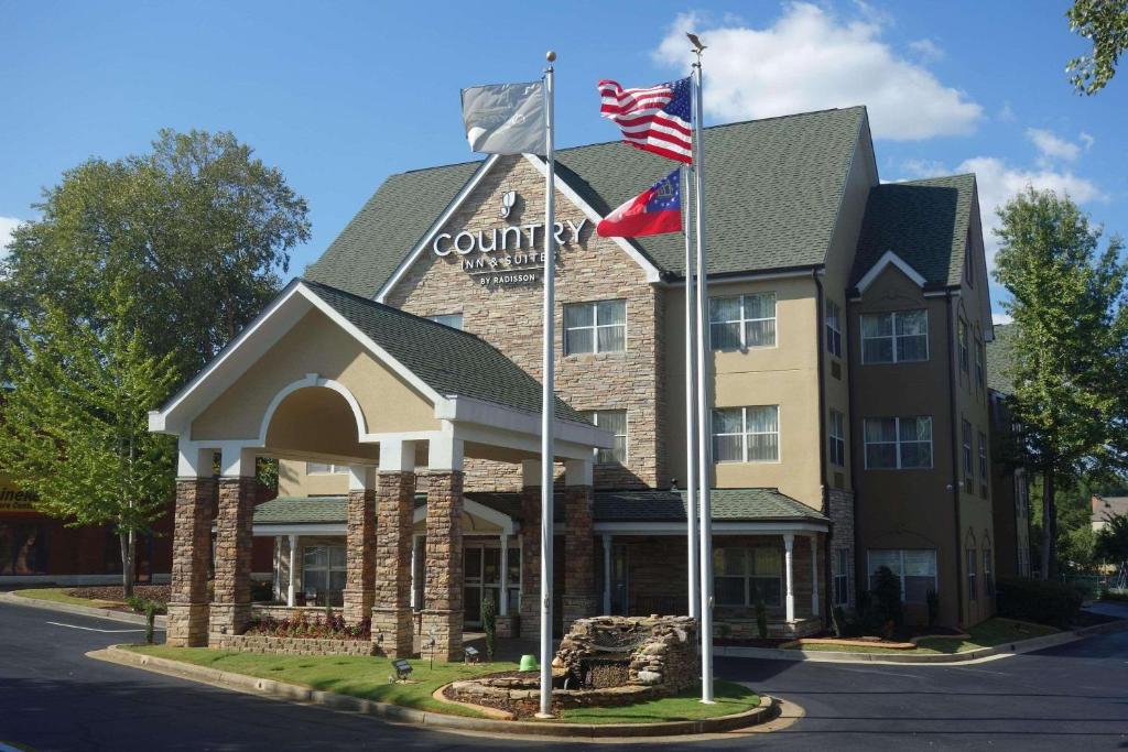 a hotel with two american flags in front of it at Country Inn & Suites by Radisson, Lawrenceville, GA in Lawrenceville