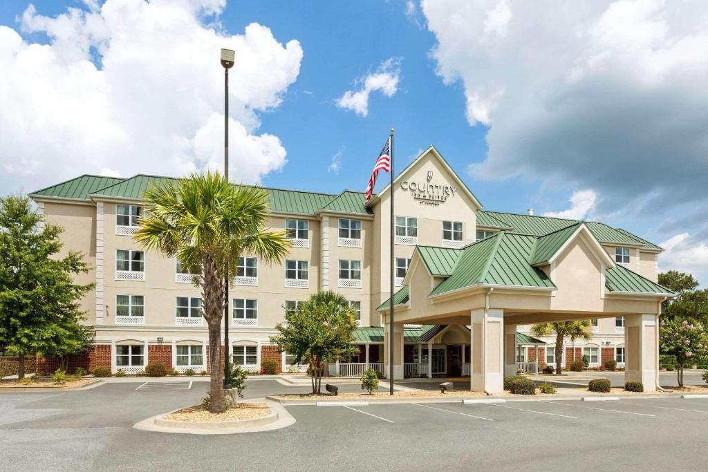 an exterior view of a hotel with an american flag at Country Inn & Suites by Radisson, Macon North, GA in Macon
