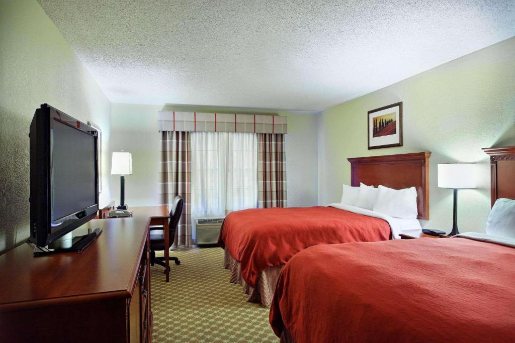 a hotel room with two beds and a flat screen tv at Country Inn & Suites by Radisson, Rock Falls, IL in Rock Falls