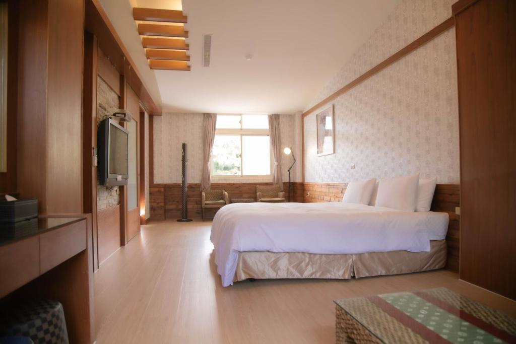 a hotel room with a bed and a television at Guanziling Lin Kuei Yuan Hot Spring Resort in Baihe