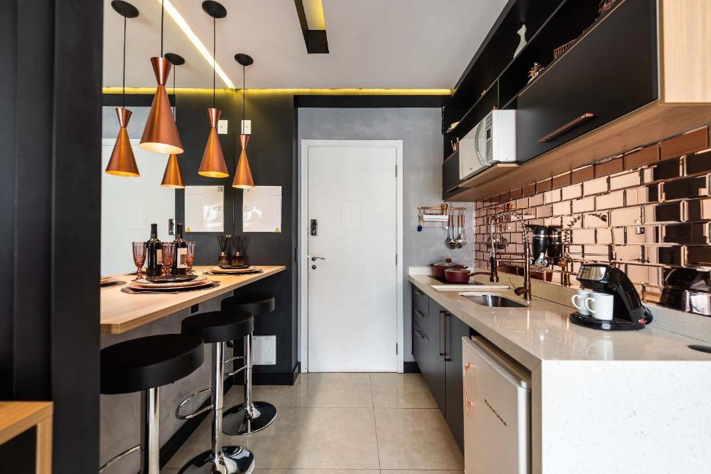 una cocina con encimera y taburetes. en MS906 Studio Encantador na Bela Vista, en São Paulo