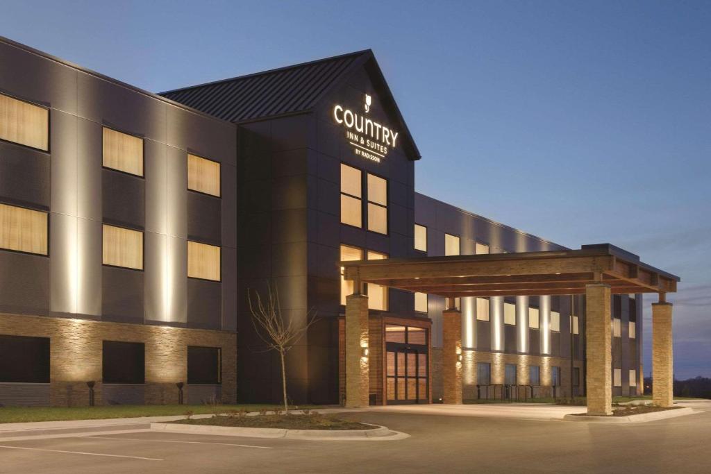a building with a sign on the front of it at Country Inn & Suites by Radisson, Lawrence, KS in Lawrence