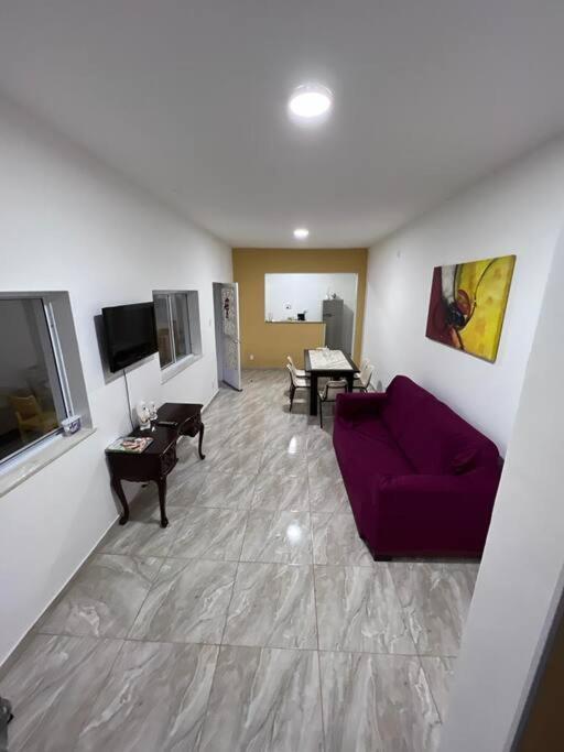 a living room with a purple couch and a table at Recanto dos Braga in Saquarema