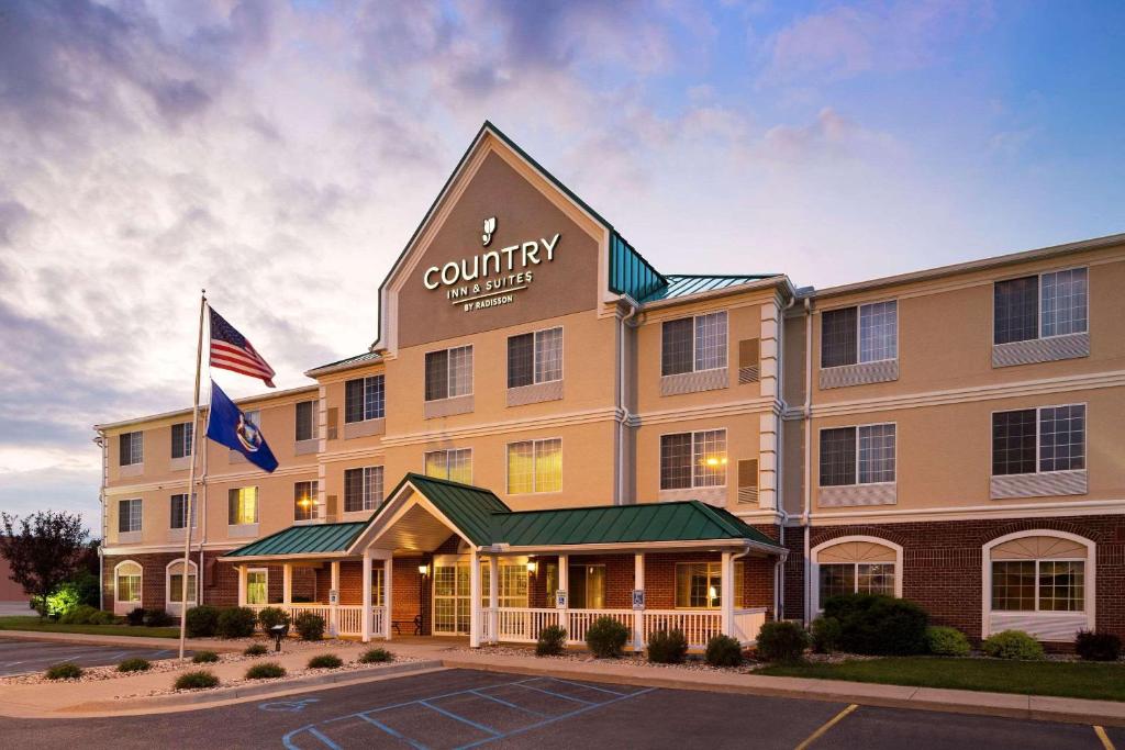 una vista exterior de un hotel con bandera americana en Country Inn & Suites by Radisson, Big Rapids, MI, en Big Rapids