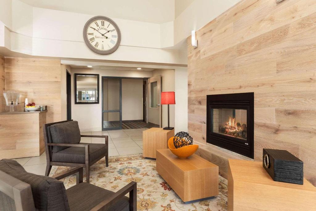 a living room with a fireplace and a clock on the wall at Country Inn & Suites by Radisson, Eagan, MN in Eagan