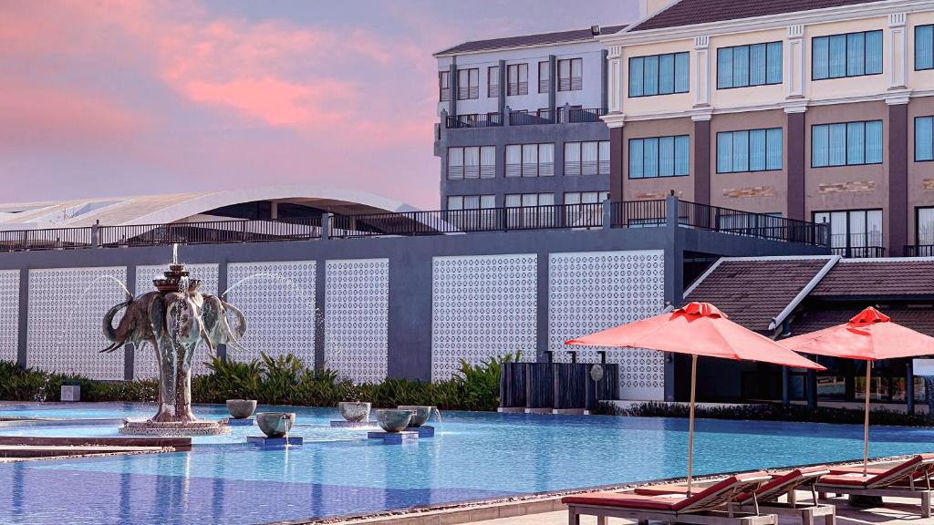 Pacific Hotel & Spa في سيام ريب: مسبح فيه كراسي ومظلات امام مبنى