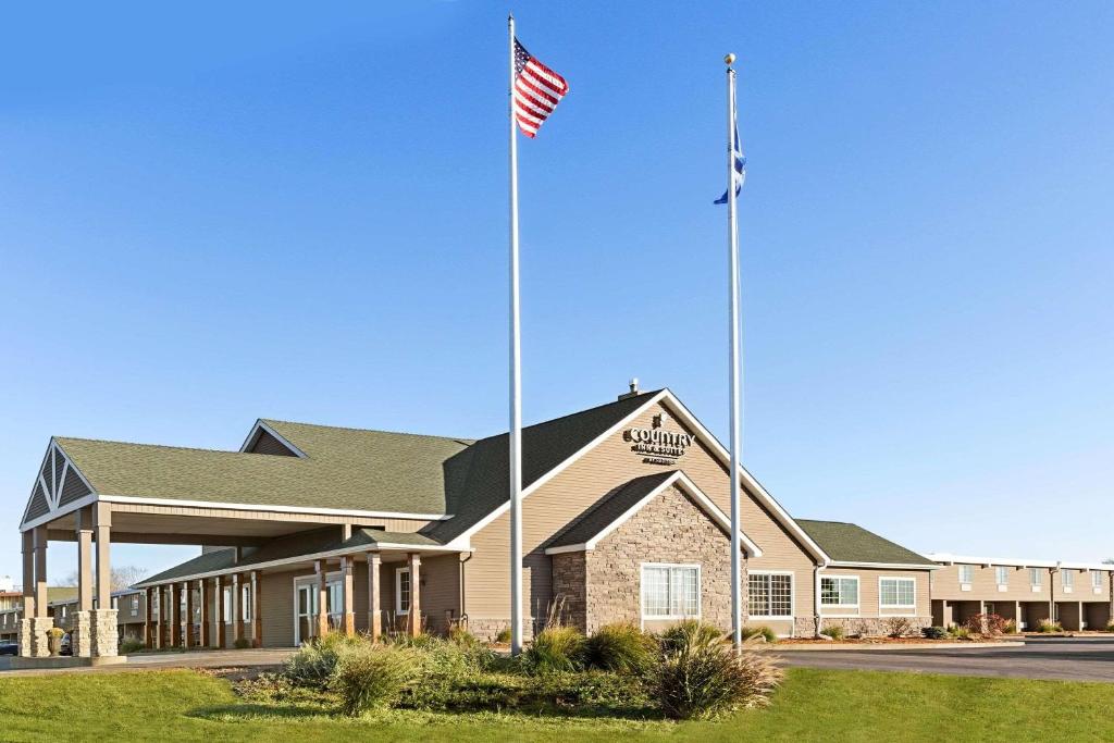 Un edificio con due bandiere americane davanti. di Country Inn & Suites by Radisson, Woodbury, MN a Woodbury