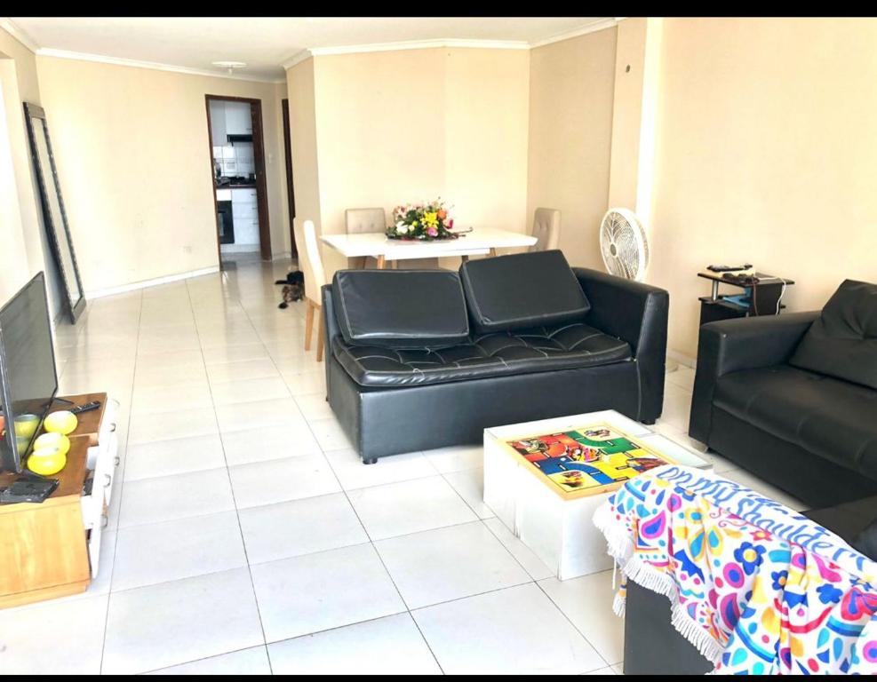 a living room with a black couch and a table at Habitación amoblada con servicios Rio mar in Barranquilla