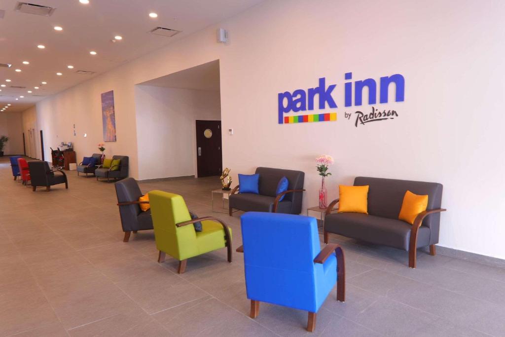 Park Inn by Radisson Mazatlan في مازاتلان: غرفة انتظار وكراسي وعلامة على الحائط