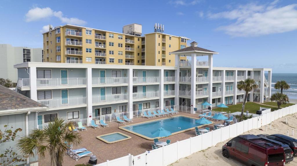 a hotel with a swimming pool and a parking lot at Coastal Waters 106 - A 1-1 Pool Side Retreat in New Smyrna Beach
