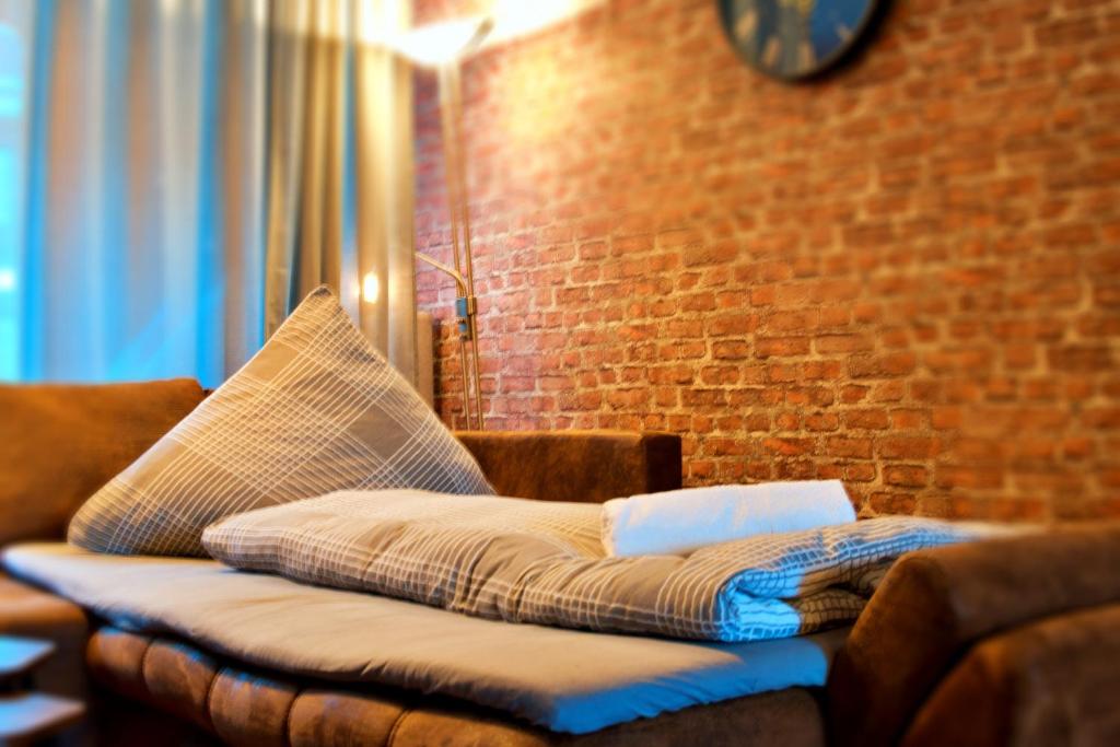 un sofá con una almohada junto a una pared de ladrillo en Industrial Style 77qm mit Balkon en Herne