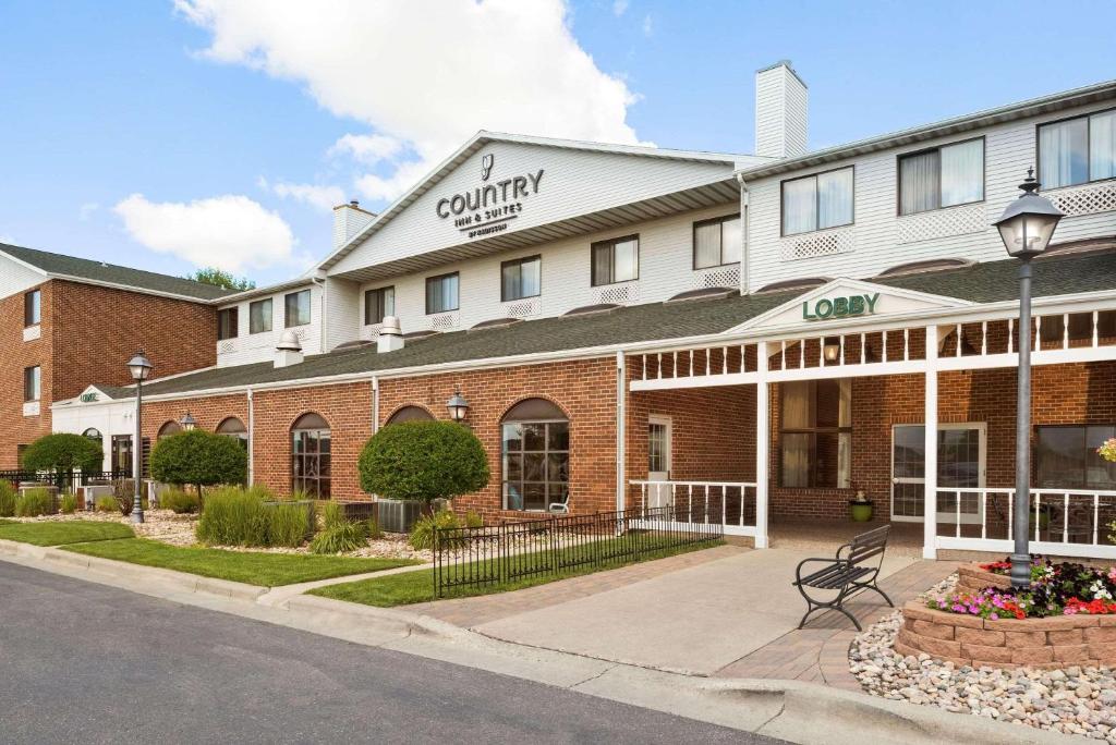 Country Inn & Suites by Radisson, Fargo, ND في فارغو: مبنى الفندق امامه مقعد