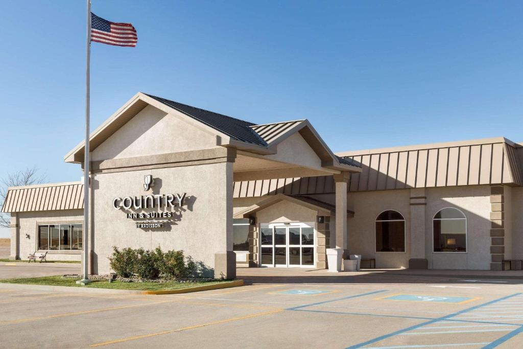 a building with an american flag in front of it at Country Inn & Suites by Radisson, Sidney, NE in Sidney