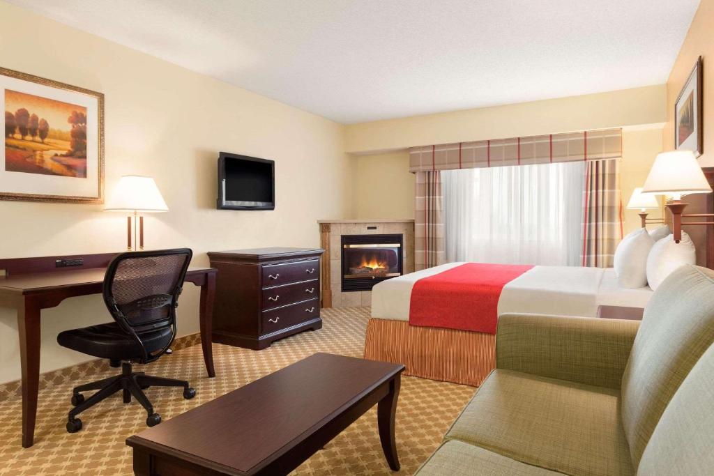 a hotel room with a bedroom with a bed and a desk at Country Inn & Suites by Radisson, Lincoln North Hotel and Conference Center, NE in Lincoln
