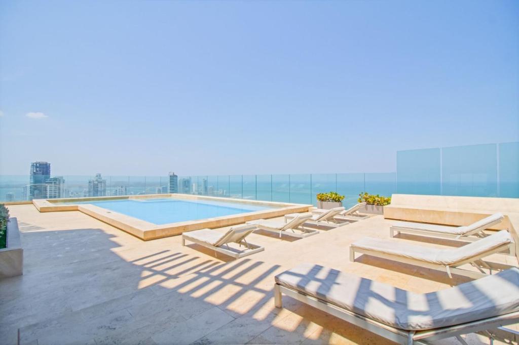 卡塔赫納的住宿－U-GO Edificio Murano Elite Bocagrande Frente al Mar，一个带躺椅的游泳池和大海