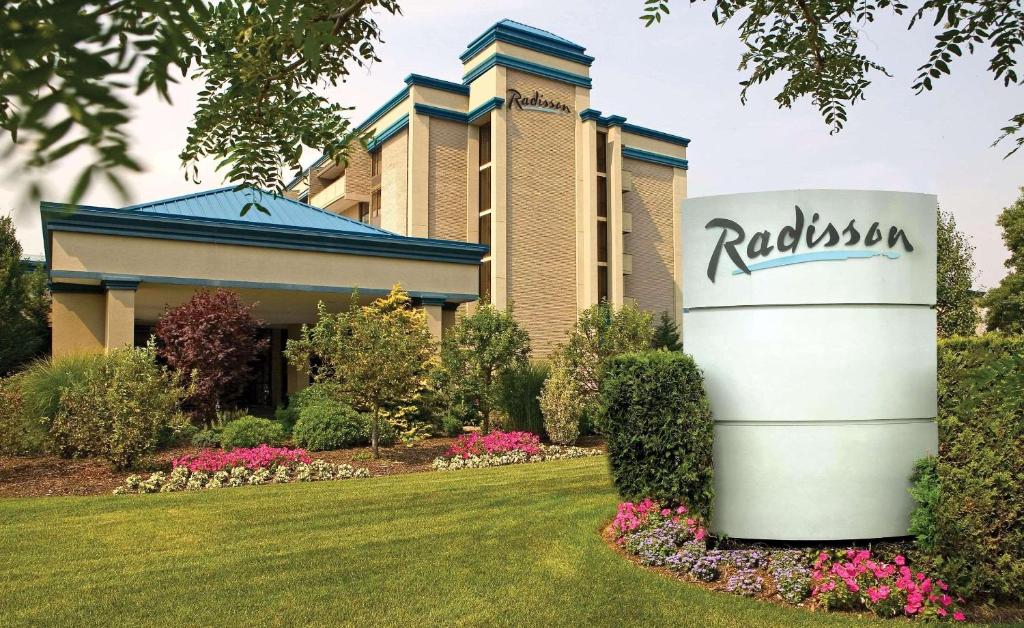 a building with a sign in front of a yard at Radisson Hotel Hauppauge-Long Island in Hauppauge