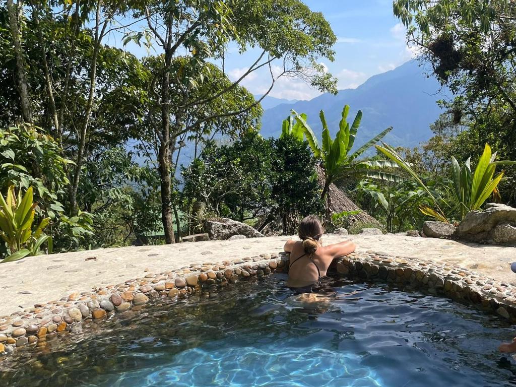 a woman is sitting in a swimming pool at Ecofinca in the mountains Azulita House in Cocorná