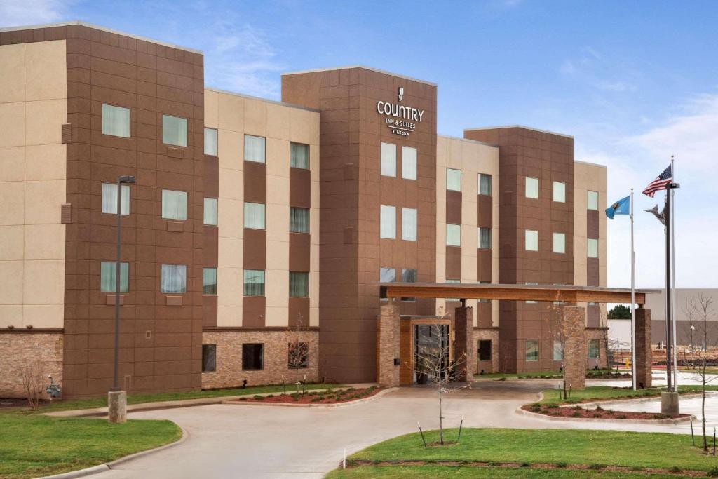 Enid的住宿－Country Inn & Suites by Radisson, Enid, OK，校园建筑前面有旗帜