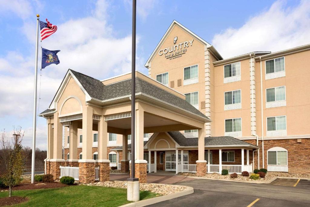 un hotel con una bandera americana delante de él en Country Inn & Suites by Radisson, Washington at Meadowlands, PA en Washington
