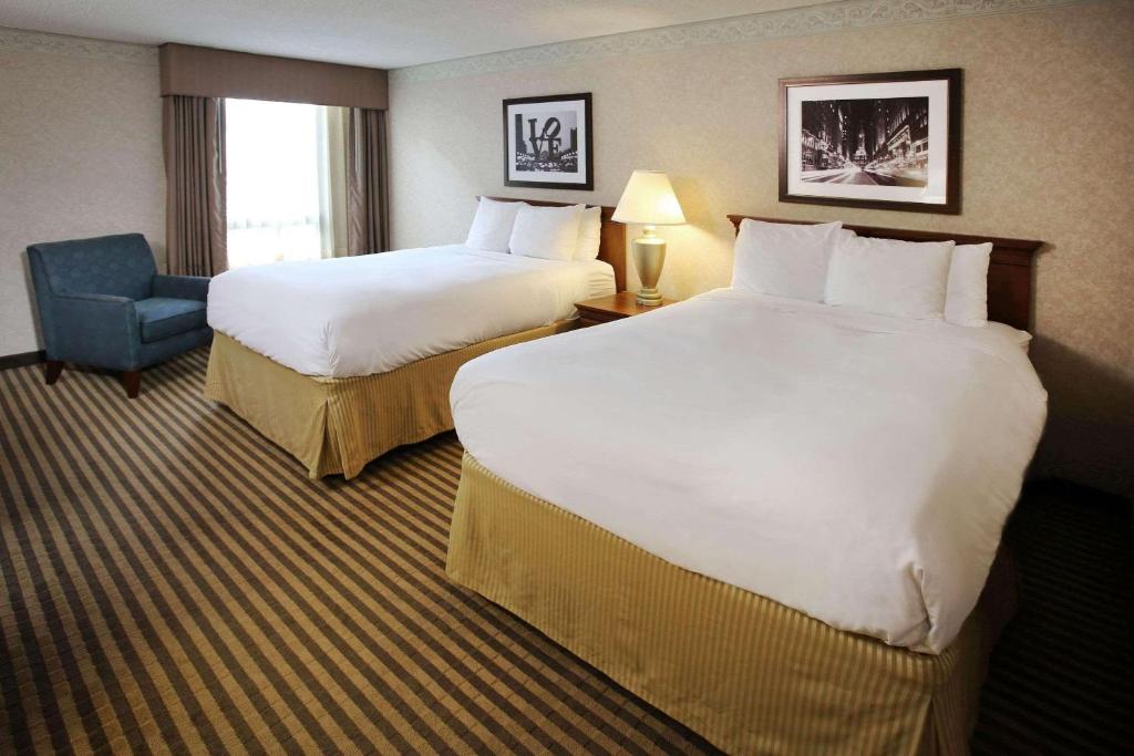 una habitación de hotel con 2 camas y una silla en Radisson Hotel Philadelphia Northeast, en Trevose