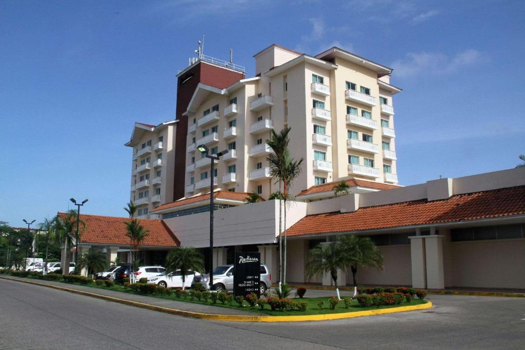 un gran edificio blanco con coches estacionados frente a él en Radisson Colon 2,000 Hotel & Casino, en Colón