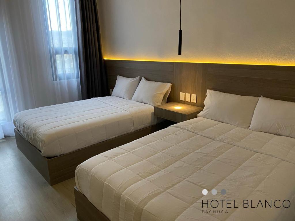 Hotel Blanco Pachuca في باتشوكا دي سوتو: سريرين في غرفة فندق مع سريرين sidx sidx